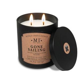 an image of the candle classic plus gone sailing. The candle is lit and the lid of the candle is placed against the candle on its side